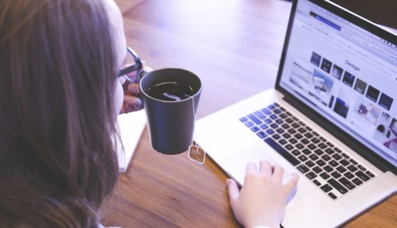 A woman drinking tea and using a laptop