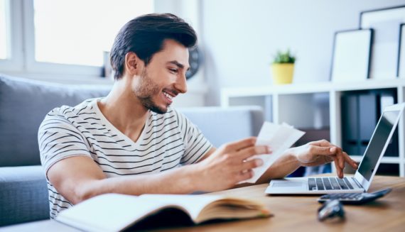 A man typing on his laptop and smiling