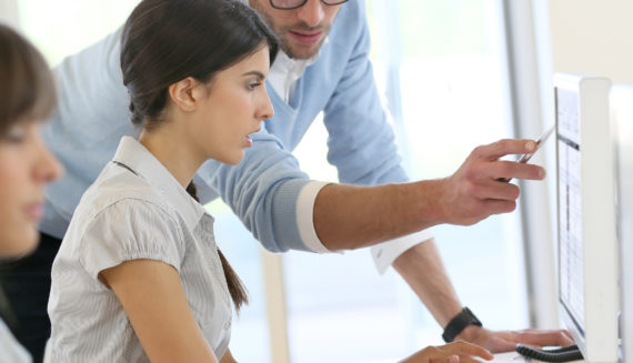 A man showing a woman something on a computer