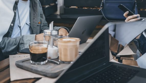 People sitting in a cafe with laptops and phones