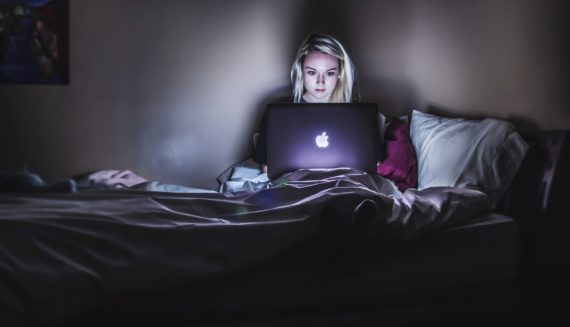 A girl sitting with a laptop in bed