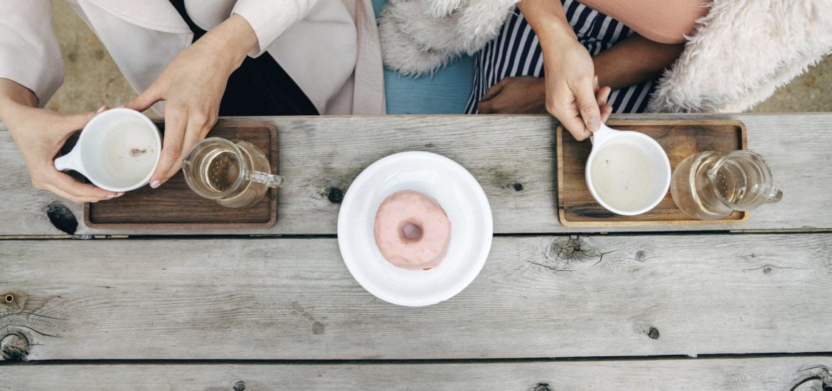 Two women with coffee and a donut